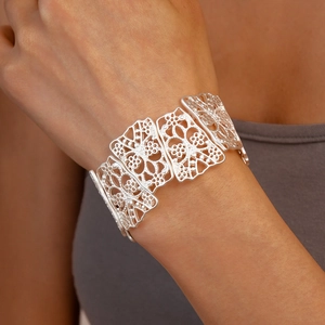 Detailed view of silver matte cuff bracelet with intricate hollow flower filigree on wrist