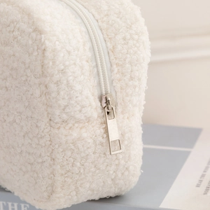 White faux shearling cosmetic travel bag with elegant silver zipper and soft texture