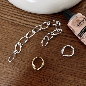 Minimalistisches Silberarmband und Lavatextur-Ringe auf einem Holzhintergrund