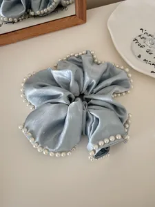 Close-up of light blue silk scrunchie with elegant white pearl trim detail