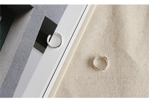 Minimalist silver ear cuffs displayed on a book edge and beige linen texture