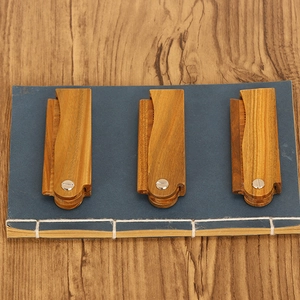 Set of three handcrafted green sandalwood folding combs on a vintage book