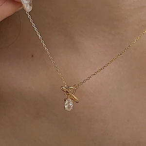 Detail of s925 silver necklace with gold plating and oval zircon pendant on a model