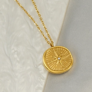 Golden North Star pendant necklace with small diamond on white ripple background