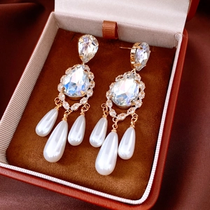 Detailed view of 18k gold plated teardrop tassel earrings with pearls on brown velvet