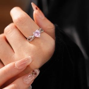 Detail of pink heart-shaped crystal ring with silver pavé split band on finger