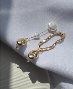 Detailed shot of asymmetric S925 baroque pearl earrings with golden geometric accents