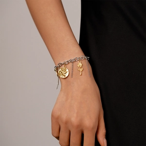 Detail of two-tone stainless steel bracelet with rose pendants and chain tassels on wrist