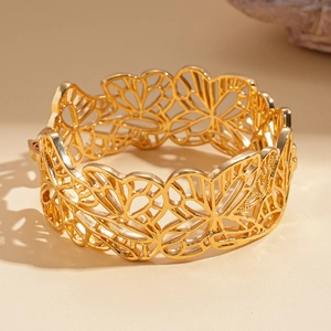 Vue détaillée d'un large bracelet doré ouvert présentant des motifs floraux évidés