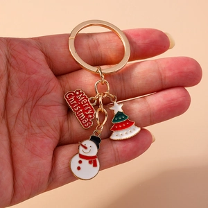 Detail of Christmas keychain with enamel snowman and tree charms on a gold ring