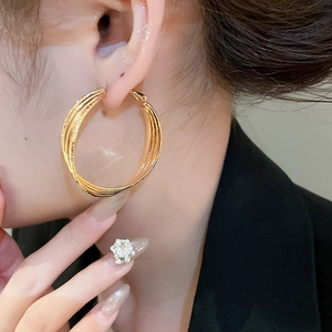 Gros plan de créoles multicouches plaquées or 18 carats sur un mannequin élégant
