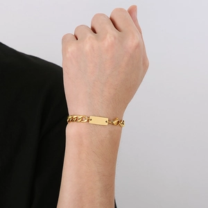 Close-up of gold titanium steel Cuban chain bracelet with a blank tag on model wrist