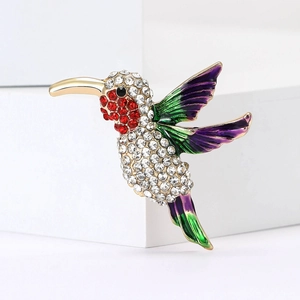 Exquisite rhinestone hummingbird brooch with colorful enamel details on a white base