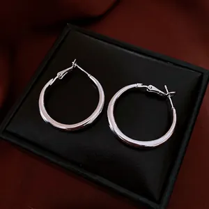 Polished silver hoop earrings with minimalist design on luxury textured display pad