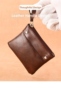Detail showing the leather pull handle and zip closure of a small brown coin purse