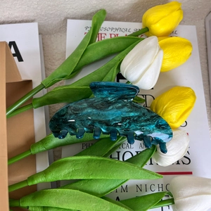 Close-up of deep green marble pattern acrylic hair claw clip with tulip background