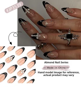 Detail of almond-shaped press-on nails with black French tips, silver crosses and rhinestones