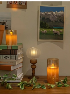 Warm glowing Christmas candle lamp on stacked books with greenery and cozy background