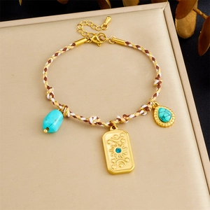 Detail of bohemian braided rope bracelet with gold embossed charms and blue turquoise
