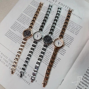 Flat lay of multiple NAIDU ladies quartz watches with metal chain straps on book pages