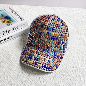 Detailed close-up of a white baseball cap featuring vibrant multi-colored beaded pearls
