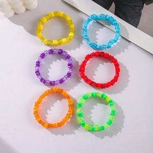 Flat lay showing six colorful acrylic star-beaded elastic bracelets on a white surface
