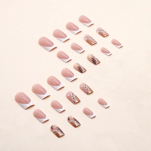 White French tip press-on nails with gold glitter and black leaf silhouettes