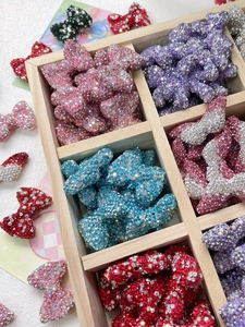 Close-up of sparkling bow-shaped charms in various colors for DIY jewelry making