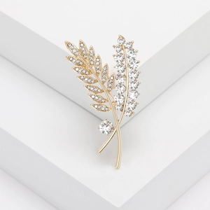Macro shot of gold leaf brooch featuring sparkling rhinestones and berry-like crystal accents