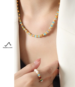 Détail d'un ensemble de collier et bague en perles de pierre colorées et acier