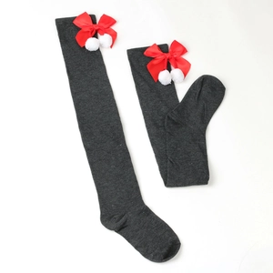 Detail of dark gray over-knee socks with red festive bows and white pom-pom accents