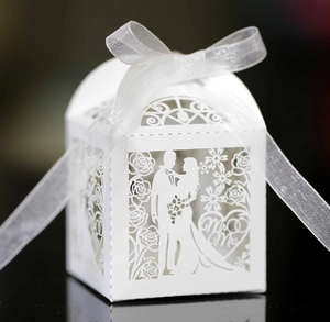 Close-up of white laser cut wedding candy box with Mr & Mrs silhouette and ribbon bow