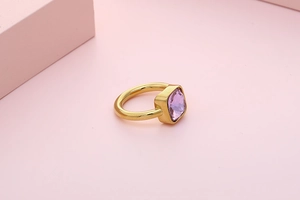 Close-up of a gold stainless steel ring featuring a square purple zircon gemstone
