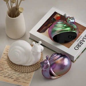 Detail of snail ornaments in white matte and metallic finishes on a minimalist background