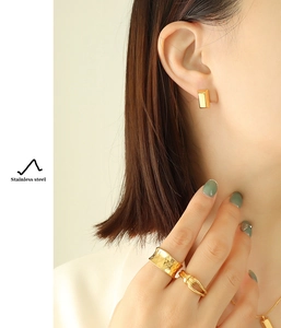 Gros plan détaillé de boucles d'oreilles en acier inoxydable doré 18 carats et bague