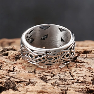 Punk style wide stainless steel Viking ring with intricate Celtic knot patterns on wood