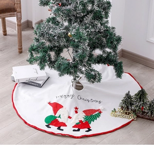 Detail of white Christmas tree skirt with red border and festive gnome embroidery