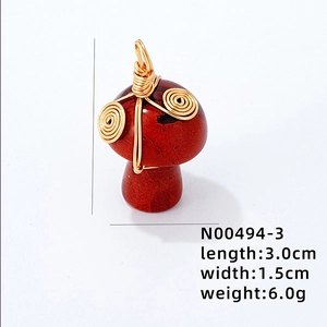 Vue macro d'un pendentif champignon en cristal rouge avec fil doré torsadé à la main