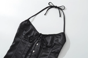 Dettaglio del top a corsetto in raso nero con fiocco intrecciato e bottoni in metallo