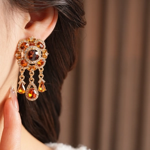 Nahaufnahme von Vintage-Barockohrringen mit bernsteinfarbenen Steinen am Modell