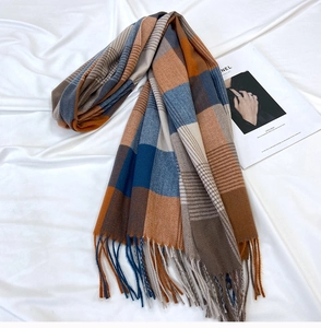 Detailed texture of thick plaid scarf with tassels in orange and navy blue tones