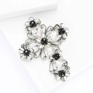 Vintage silver alloy cross brooch with rhinestones and black beads on white stand
