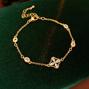 Detailed macro view of golden clover bracelet with zircon on green velvet background