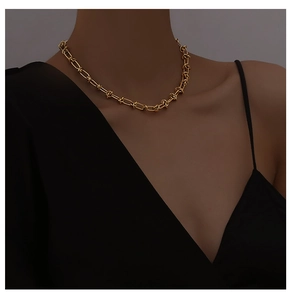 Close-up of a 18K gold-plated knotted thorn chain necklace worn on a woman's collarbone