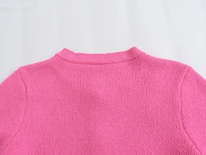 Detailed macro view of the bright pink knit cardigan neckline and ribbed texture