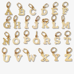 Set of 26 gold stainless steel alphabet pendants from A to Z on white background