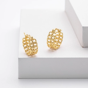 Detail of gold twisted chain hoop earrings on a minimalist white geometric display