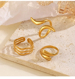 Three irregular 18K gold plated minimalist wrap rings displayed on sand textured stone