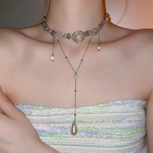 Detail of layered necklace with vintage medallions, pearls, and teardrop crystal pendants
