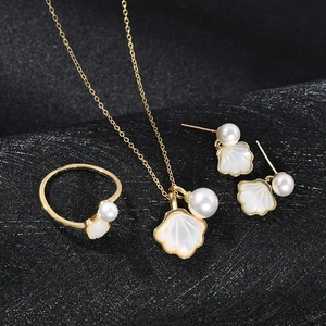 Macro detail of gold jewelry set with necklace earrings and shell pearl rings